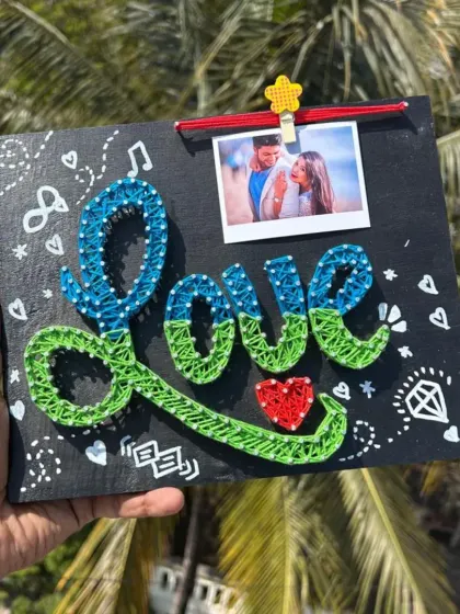 A "Love" themed string art piece with a clip to hold a special photo. The board is decorated with cute doodles, making it a fun and romantic gift.