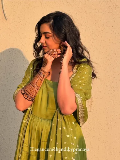 A lovely photo of the bride admiring her henna, a mix of traditional and modern design elements.