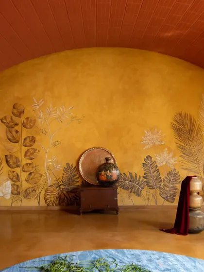 The feature wall in the Madhura house, finished in yellow oxide with delicate leaf imprints, acts as an artistic extension of the garden landscape just outside.