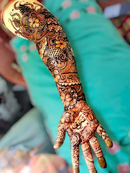 A full view of a single bridal arm, covered from fingertips to elbow in beautiful henna.