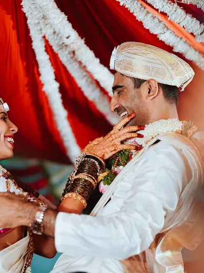 A joyful, candid moment between the bride and groom during their wedding ceremony, surrounded by the vibrant colors of the decor.