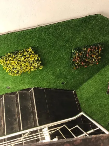 Another staircase idea. I covered the wall with neat artificial grass and added small, colorful plant panels as accents. It's a great way to decorate a high wall.