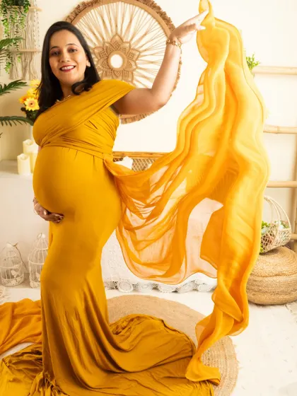 A fun and interactive shot, with the mother-to-be playfully tossing the fabric of her yellow gown.