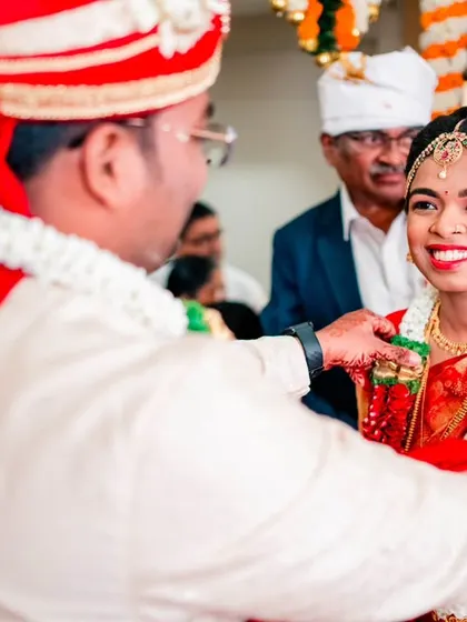 The groom placing the garland on the bride, a joyful moment from their Maharashtrian wedding ceremony.