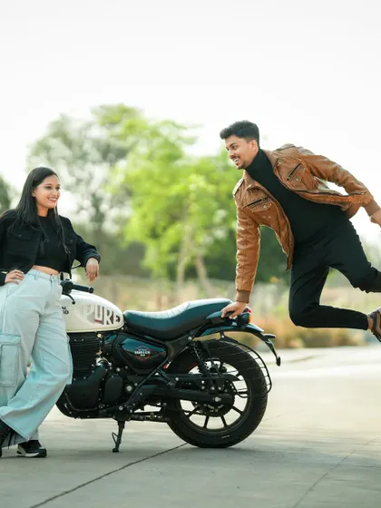 A fun, action shot of the groom jumping playfully next to his partner and a motorcycle.