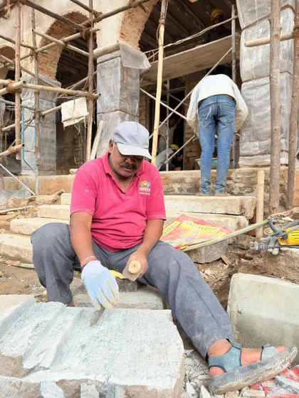 A close-up of a stonemason at work. His focus and skill are representative of the many artisans we partner with to execute our heritage conservation projects with precision and care.