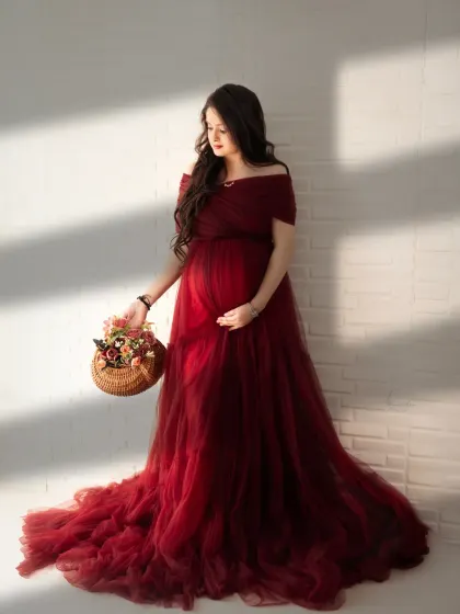 The beauty of natural light. Here, the sunlight streaming through the window creates a soft, warm glow on this mom-to-be in a rich, deep red tulle gown.