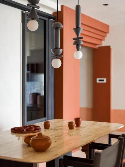 A close-up of the custom light fixtures and the travertine dining table. The design is all about celebrating natural materials and handcrafted details.