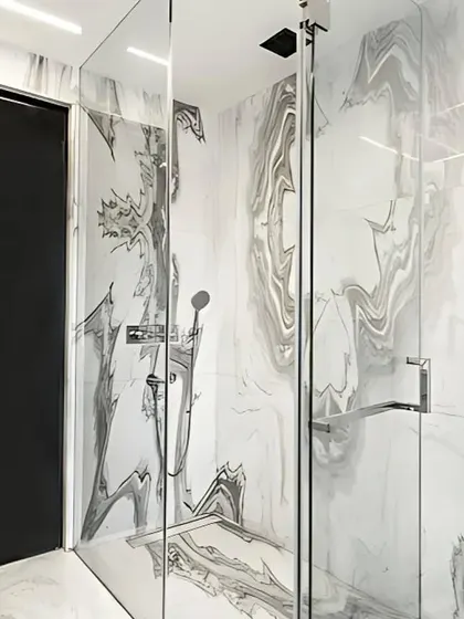 The walk-in shower in the executive bathroom continues the theme of seamless luxury. The book-matched Satvario Gold stone extends into the shower area, enclosed by frameless glass to maintain an open and uncluttered aesthetic.
