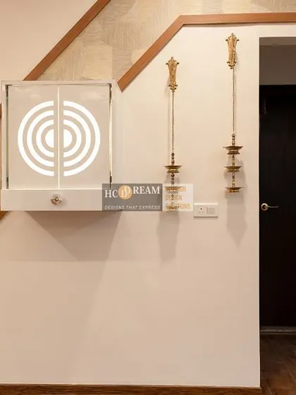 A closer view of the minimalist pooja unit, showing the elegant brass hanging lamps that frame the space and add a traditional touch.