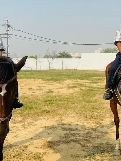 Two young riders on their horses, equipped with helmets and proper gear, ready for their lesson to begin.