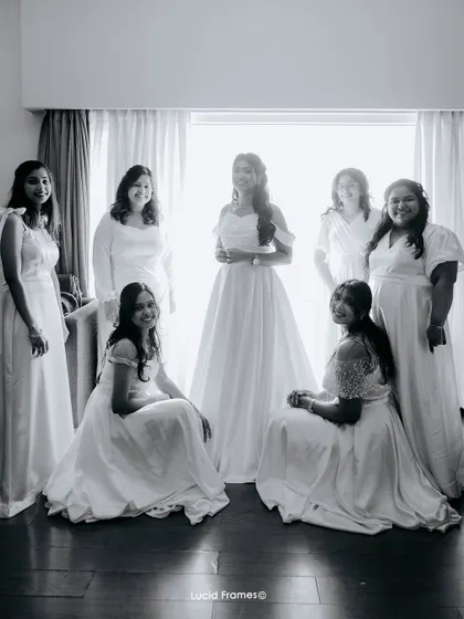 A beautiful black and white portrait of the bride and her bridesmaids in their white dresses, captured with soft window light.