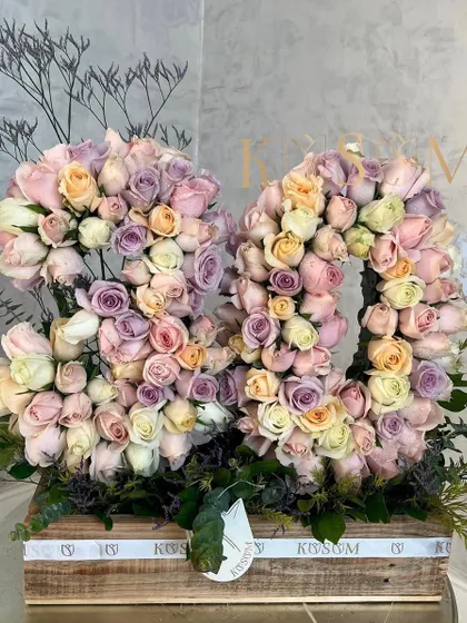 Celebrating a milestone 80th birthday with a 'Dreamland' arrangement. These floral numbers are composed of a beautiful pastel mix of lavender, baby pink, peach, and white roses, set in our rustic wooden box.