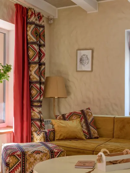 A cozy corner featuring geometric patterns on the curtains and ottoman, balanced by earthy wall tones.