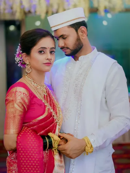A classic portrait of the couple. The groom's white kurta and the bride's pink saree create a look of simple, understated elegance.