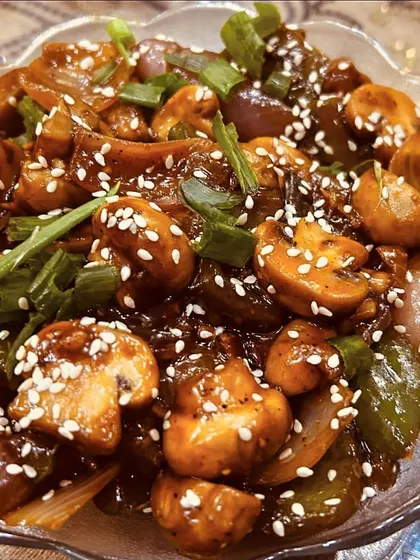 A bowl of delicious Chilli Mushroom. It has a perfect balance of spicy and savory flavors, with fresh mushrooms and crunchy vegetables.