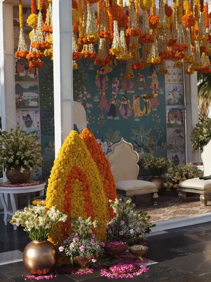 A beautiful, traditional Pelikuthuru setup in Udaipur, featuring a Pichwai art backdrop, hanging marigolds, and regal seating.