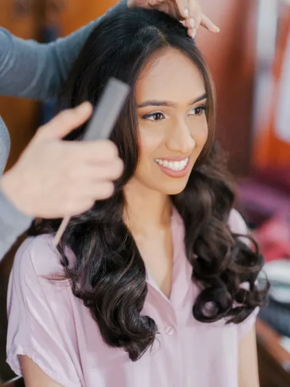 The hair is just as important as the makeup. This shot captures the process of creating soft, romantic waves for a beautiful and timeless bridal hairstyle.