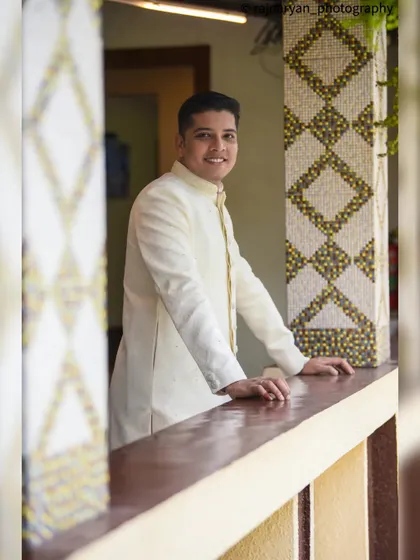 A more casual and approachable portrait of the groom smiling. This image captures his happy and relaxed mood on his special day.