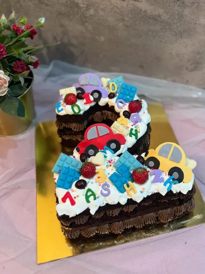 A number "2" monogram cake with a fun car theme. This chocolate cake is perfect for a toddler's birthday, decorated with colorful fondant cars.
