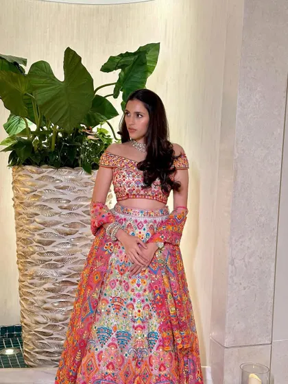 A vibrant and colorful off-shoulder lehenga by Abu Jani Sandeep Khosla. The intricate patterns and bright hues make this a perfect outfit for a festive occasion like a mehendi or sangeet.