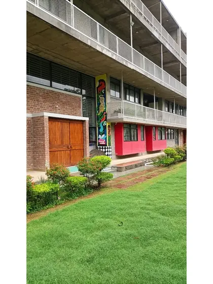 The Eklavya campus in Bhopal, where the building's design actively integrates with nature. The facade provides nesting spaces for birds, and the grounds are lush with plants, creating a living, breathing learning environment.