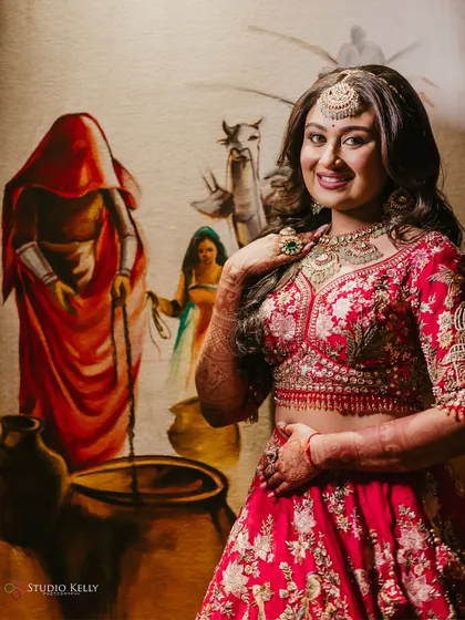 A beautiful bridal portrait, with the bride posing against a traditional Rajasthani painting.