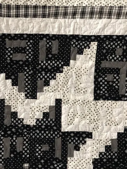 A detail shot of a black and white Log Cabin Star quilt, showing the background quilting.