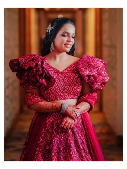 A portrait of the bride in her stylish red reception lehenga. Her confident pose and elegant hairstyle are perfectly captured.