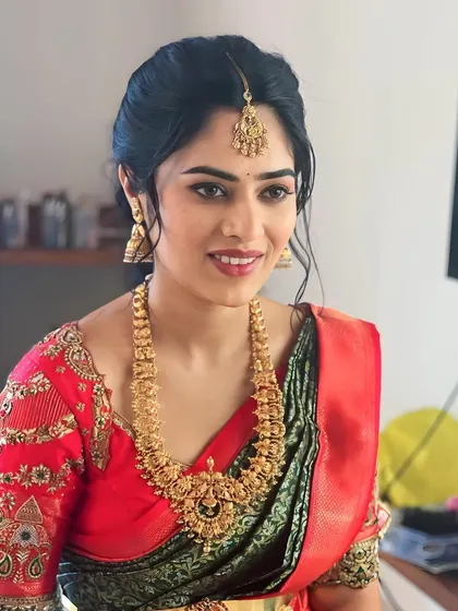 A classic South Indian bridal look. The red and green saree is paired with traditional gold jewelry and makeup that features a defined eye and a warm lip.