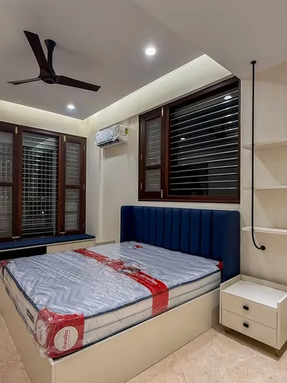 This kid's bedroom is designed to be timeless, a space that can grow with the child. The deep blue upholstered headboard adds a pop of color, while the window seat provides a cozy spot for reading.