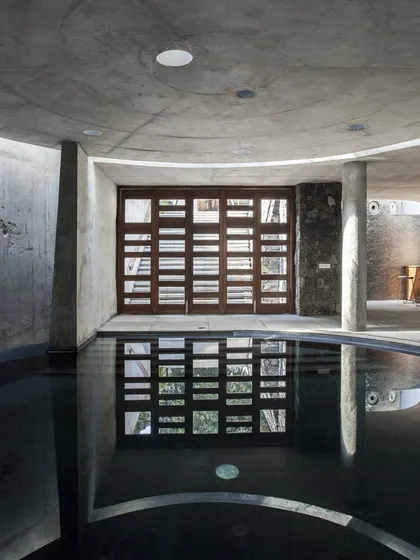 The subterranean pool at K-Lagoon is a serene, contemplative space. Circular skylights in the concrete ceiling cast soft light onto the dark water, creating a tranquil atmosphere.