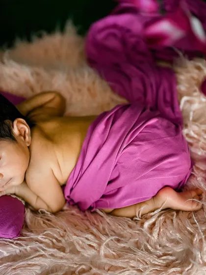 A classic side-lying pose on a fluffy pink rug. The simple setup allows the baby's peaceful sleep to be the main focus.