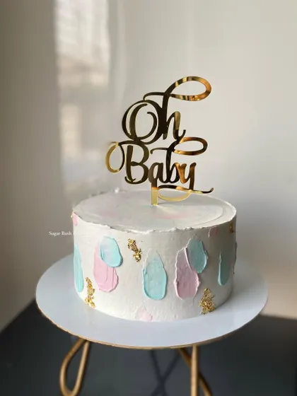 An abstract and modern baby shower cake. The simple "Oh Baby" topper and pastel color palette create a chic and stylish look for the celebration.