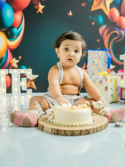 A look of surprise after the first smash. The colorful balloon backdrop and festive props create a perfect party atmosphere for this 'ONE-derland' theme.