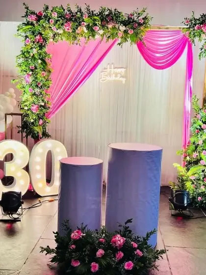 A beautiful floral setup for a 30th birthday or anniversary. The pink draping and flower arch create a soft and romantic look.