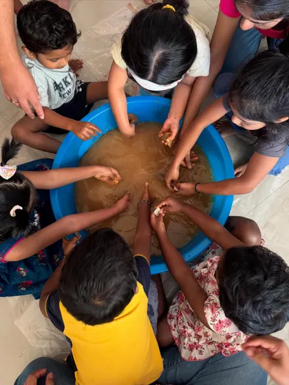 A top-down view of teamwork and discovery. In our mud play sessions, children gather around to feel the texture of the earth, working together and sharing the sensory experience. It is a fantastic group activity that encourages social interaction and collaborative play.