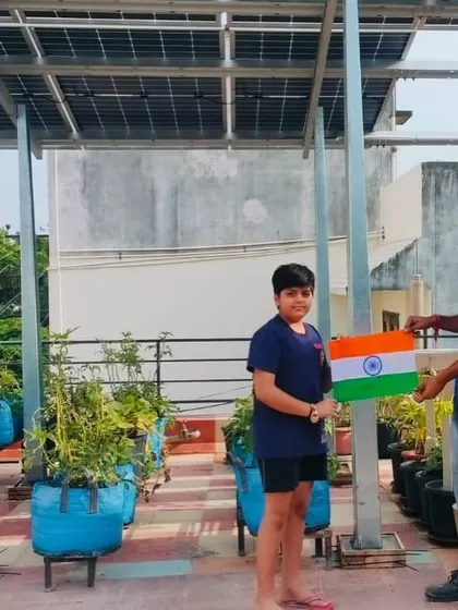 A young boy and our team member hold the Indian flag on their rooftop, a symbol of a bright, self-reliant future.