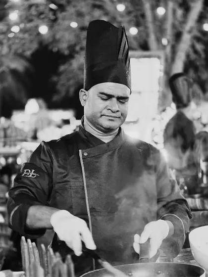The steam rising from the pan tells a story of flavour being born. This black and white image captures a chef in action, showcasing the dynamic and hands-on nature of our live cooking setups.