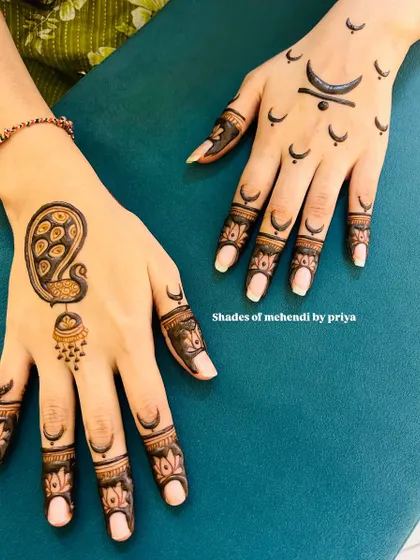 A unique combination of modern and traditional. One hand has a minimalist moon design, while the other features a classic peacock and jhumka motif.