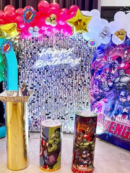 An Avengers-themed birthday setup with a silver shimmer wall and character-printed pedestals.