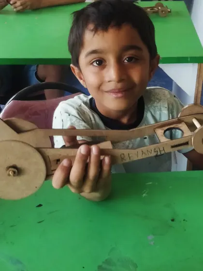 With his name proudly written on it, this young builder shows off his finished rubber-powered car.