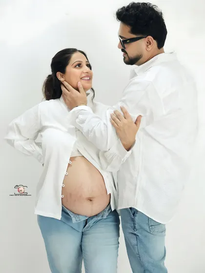 Sometimes the most beautiful moments are the simplest. This casual studio portrait, with the couple in classic jeans and white shirts, brings the focus to the pure joy and connection as they admire the baby bump.