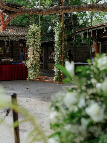 A floral swing decorated with greenery and pastel flowers, set in the venue's courtyard.