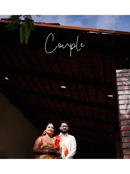 A classic couple portrait taken at their outdoor wedding venue, showcasing their traditional outfits and the beautiful architecture.