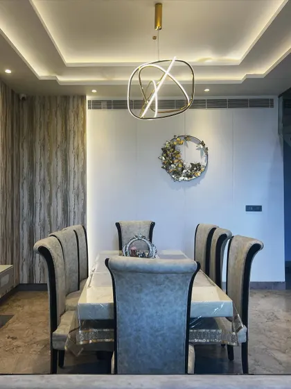 This dining area combines a textured wallpaper accent wall with a modern pendant light and classic high-back chairs for a sophisticated, layered look.