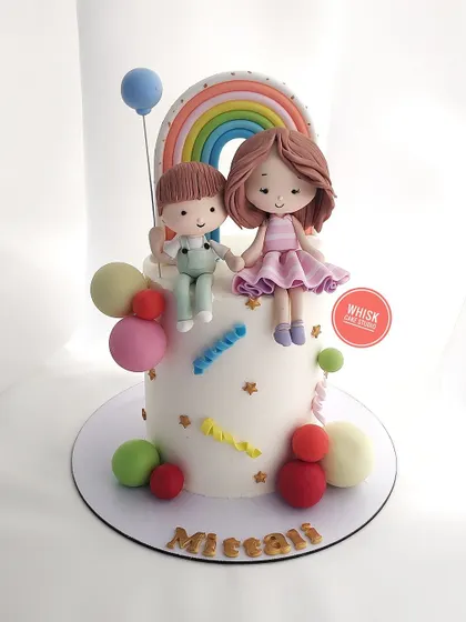 The ideal sibling cake. This design features handcrafted figurines of a brother and sister sitting together under a pastel rainbow.