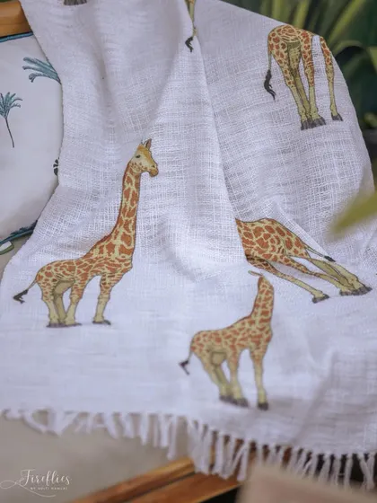A custom-printed throw blanket with a giraffe pattern, draped over a sofa to add another layer of thematic detail and comfort.