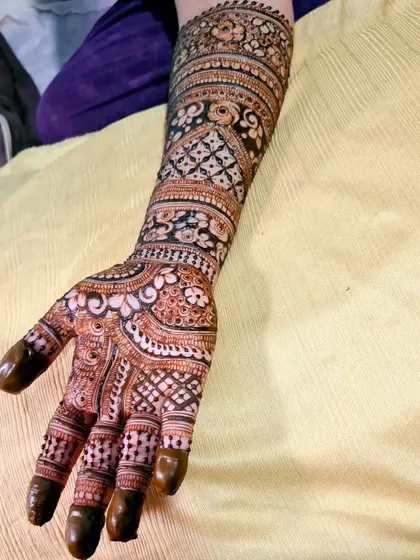 A detailed henna design for an engagement ceremony. The artwork covers the hand and arm with a variety of beautiful patterns.
