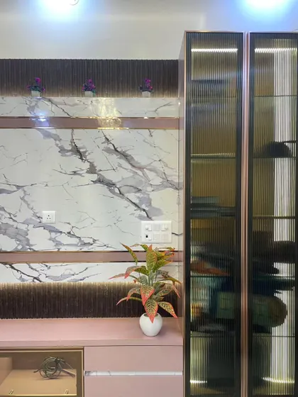 A close-up of a TV unit we designed. The combination of pink laminate, marble-finish panels, and fluted glass display cabinets creates a unique and modern look.